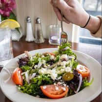 Picture of greek salad being eaten by a person with a fork